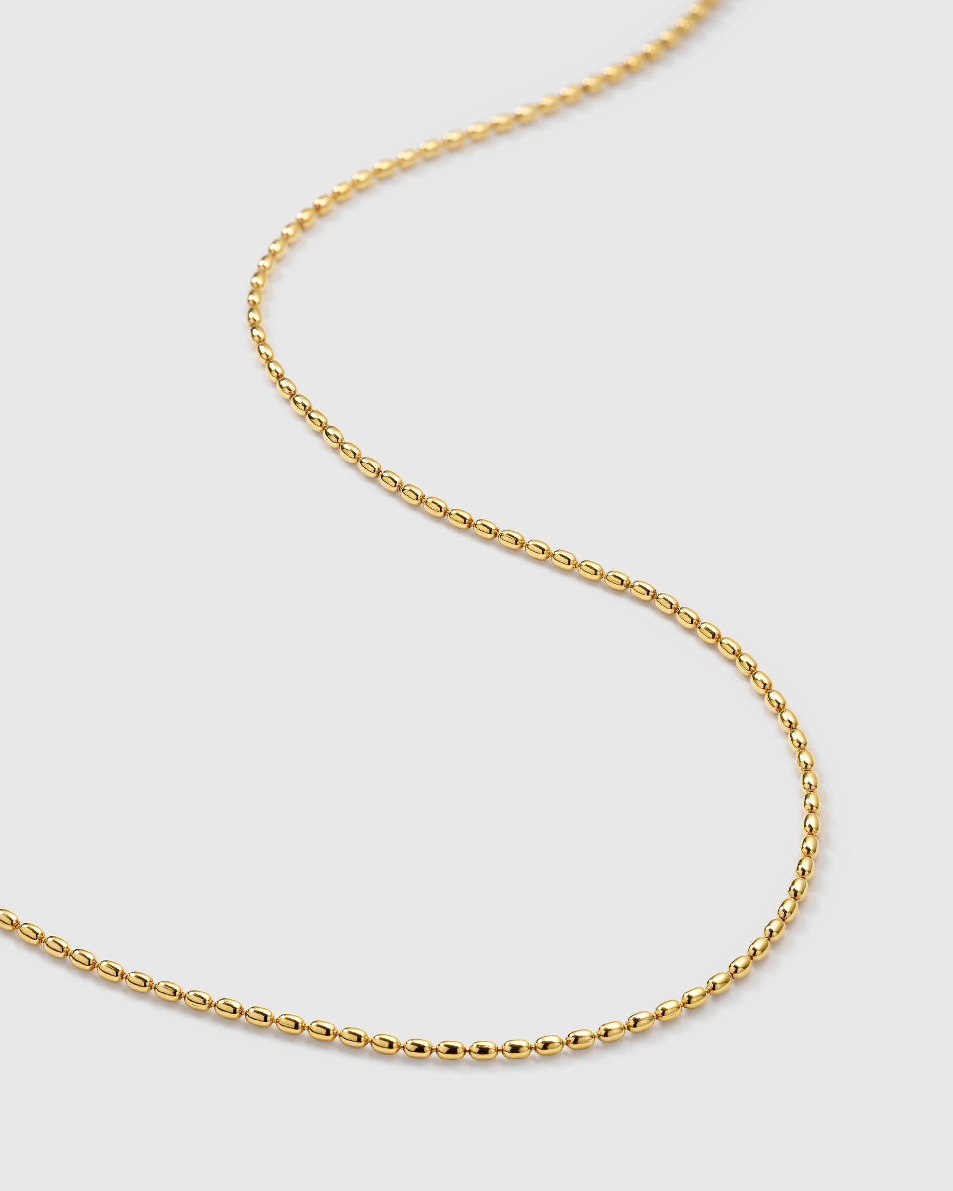 A product shot of the Lunetta Necklace in gold, showing a close-up of its unique chain composed of small, interconnected oval beads.