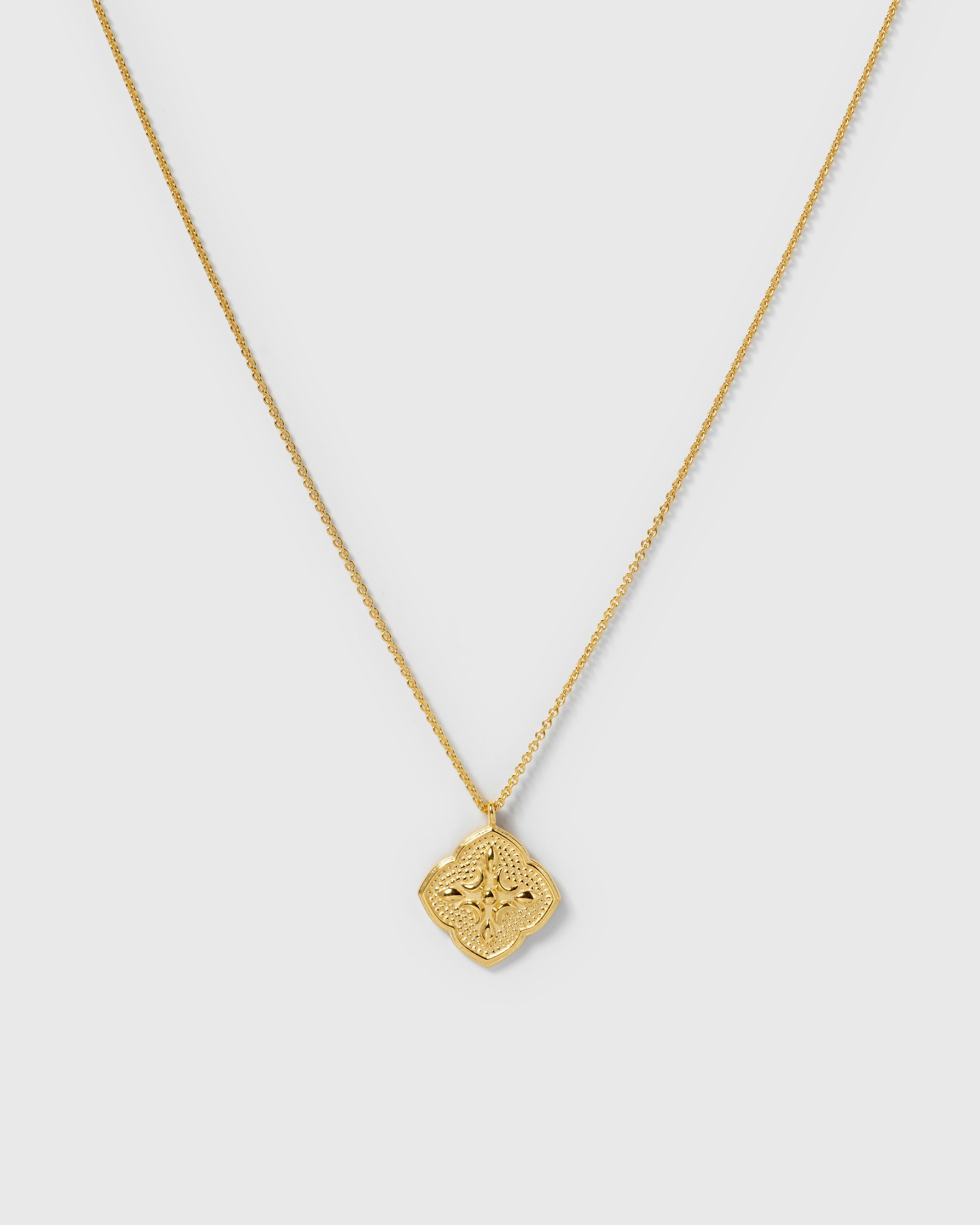 A product shot of the Luna Necklace in gold, featuring a delicate chain and an ornate, quatrefoil-shaped pendant with detailed engravings.