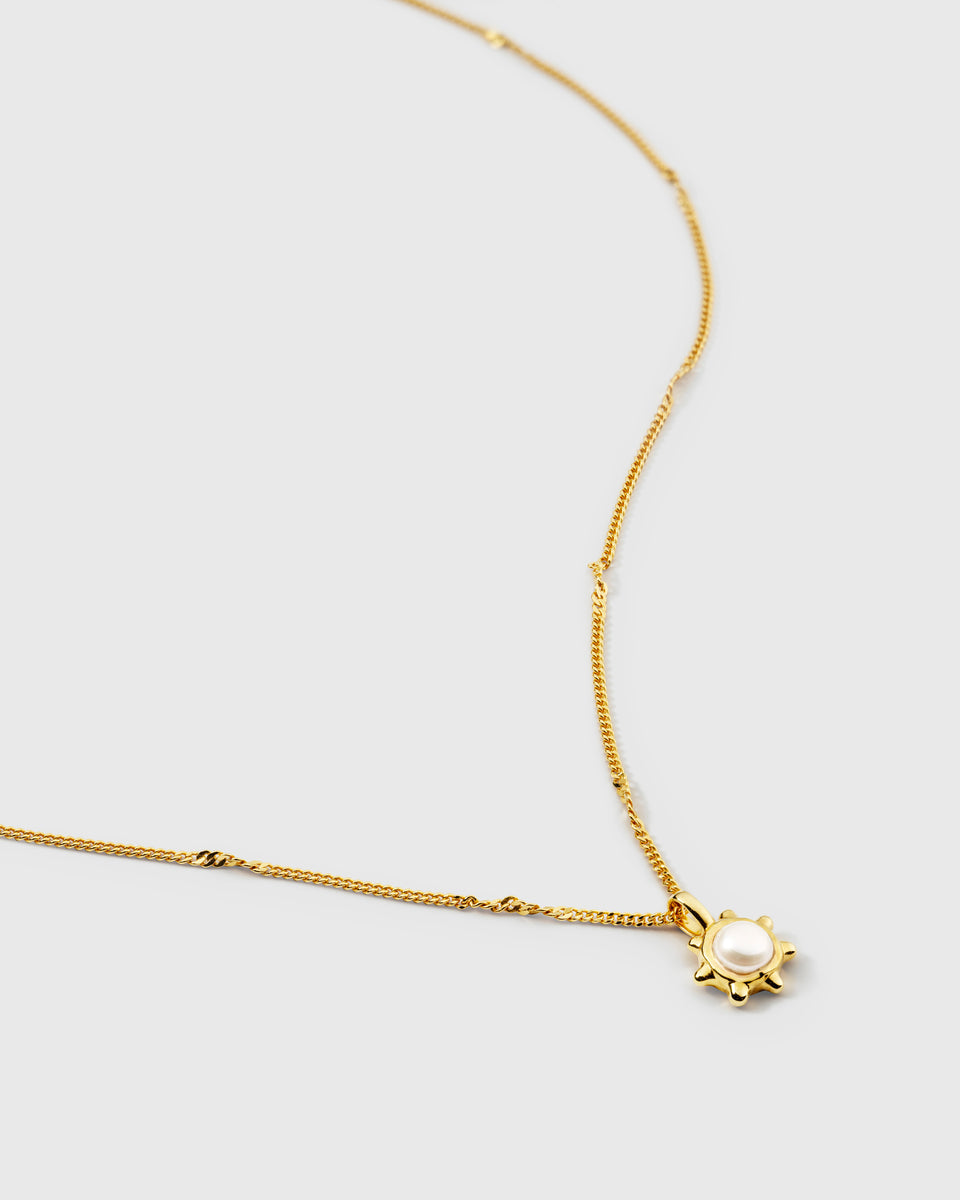 A gold necklace featuring a delicate beaded chain and a sun-shaped pendant with a central freshwater pearl.