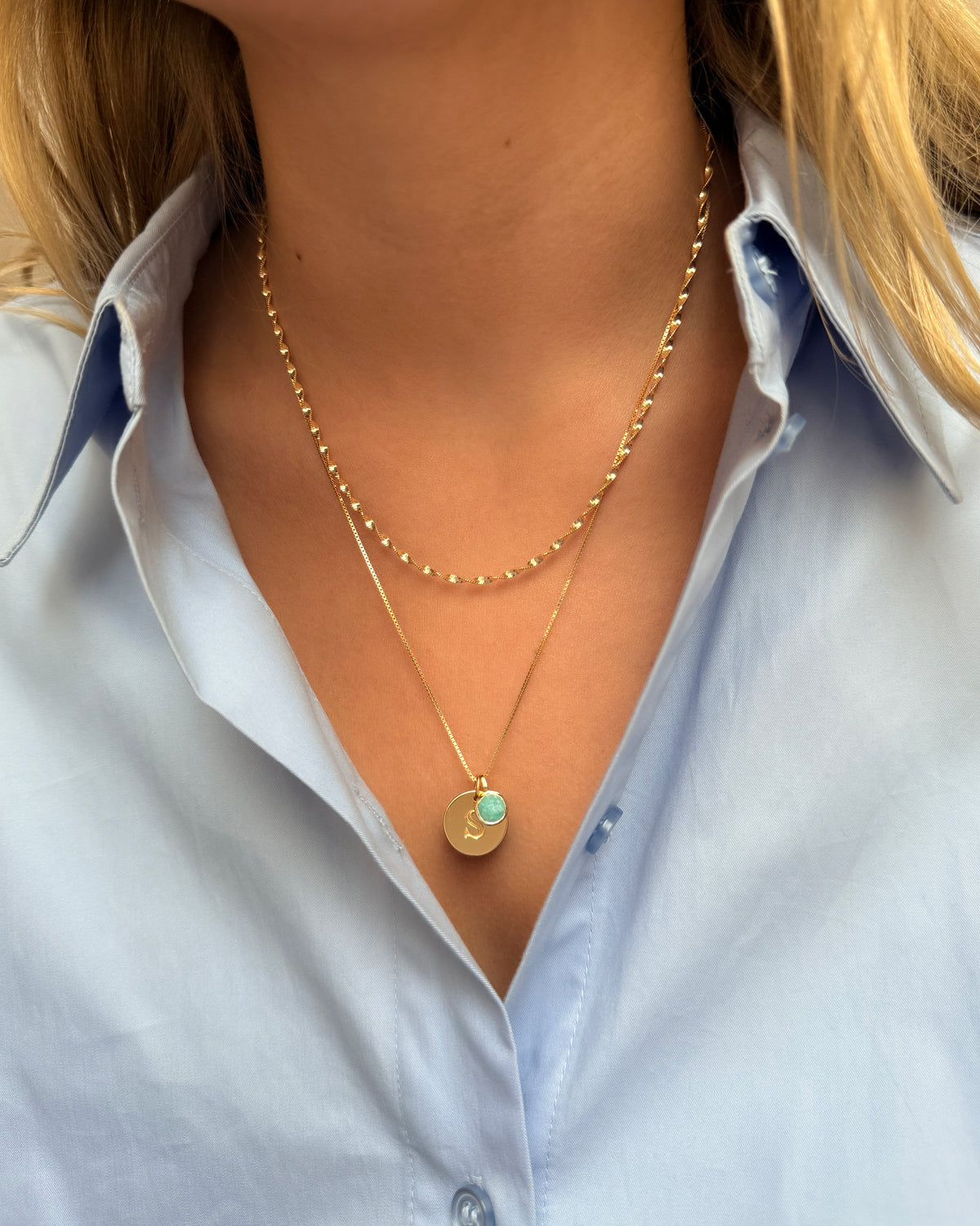 Layered gold necklaces with a December birthstone turquoise amazonite pendant and a letter charm.