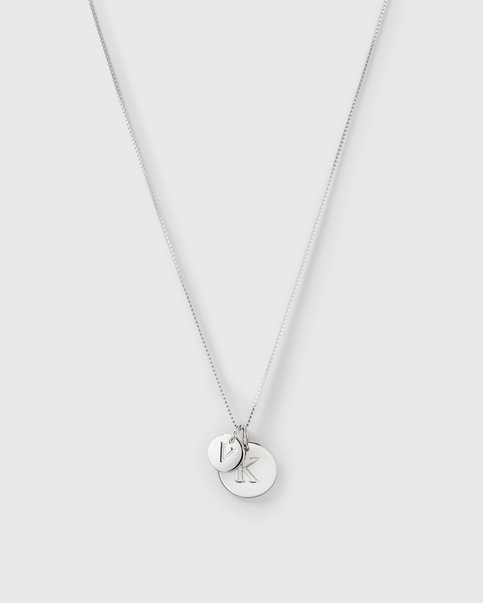 A product shot of a silver necklace featuring the Beloved Big Letter 'K' pendant styled with the smaller Beloved Mini Letter 'V' pendant.