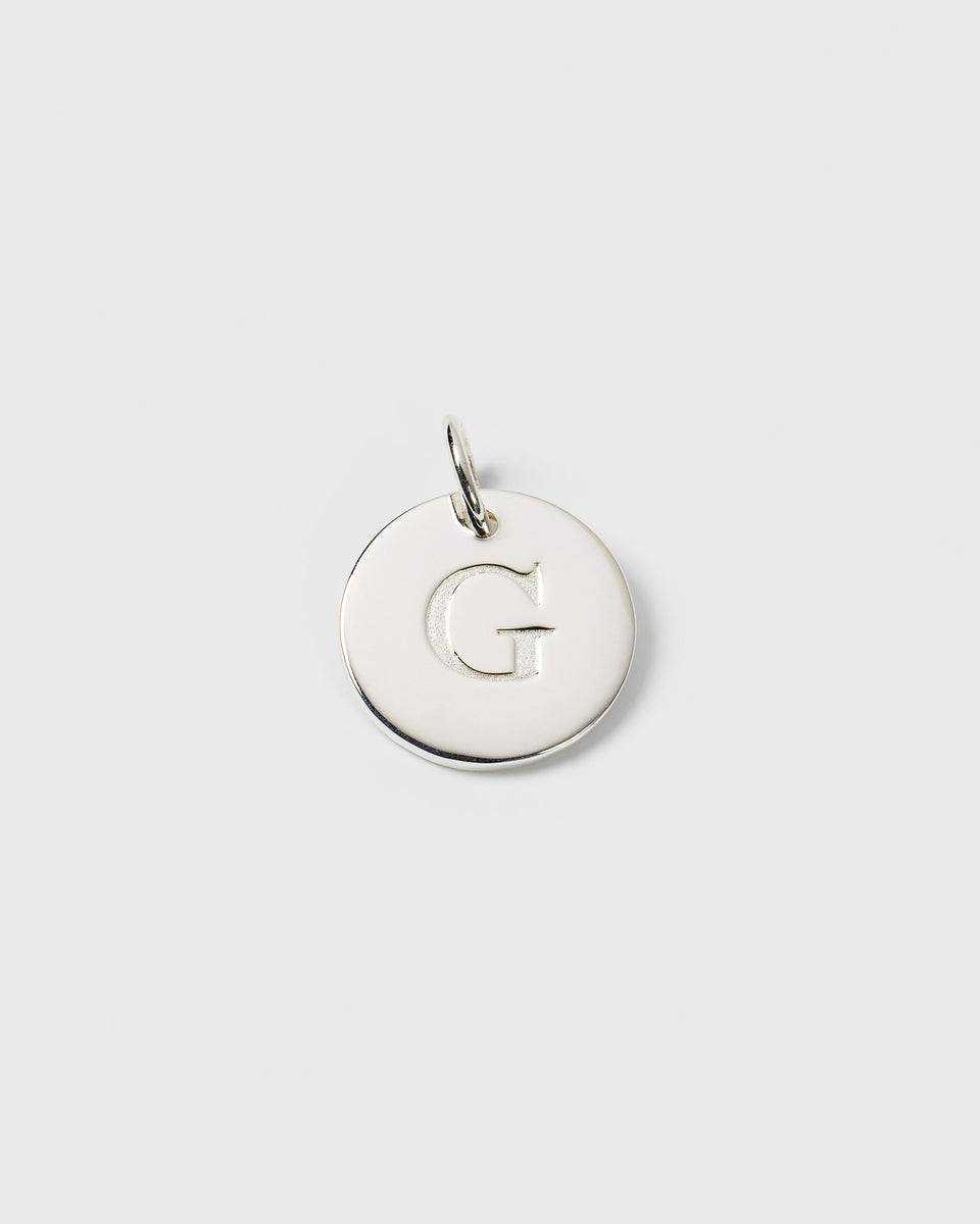 A product shot of the Beloved Big Letter Silver pendant, featuring the letter 'G' engraved on a round charm.