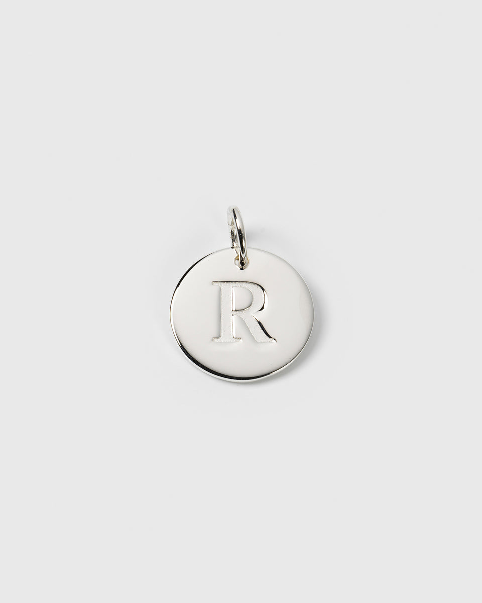 A product shot of the Beloved Big Letter 'R' charm in silver, which is a round pendant with the letter engraved on the front.
