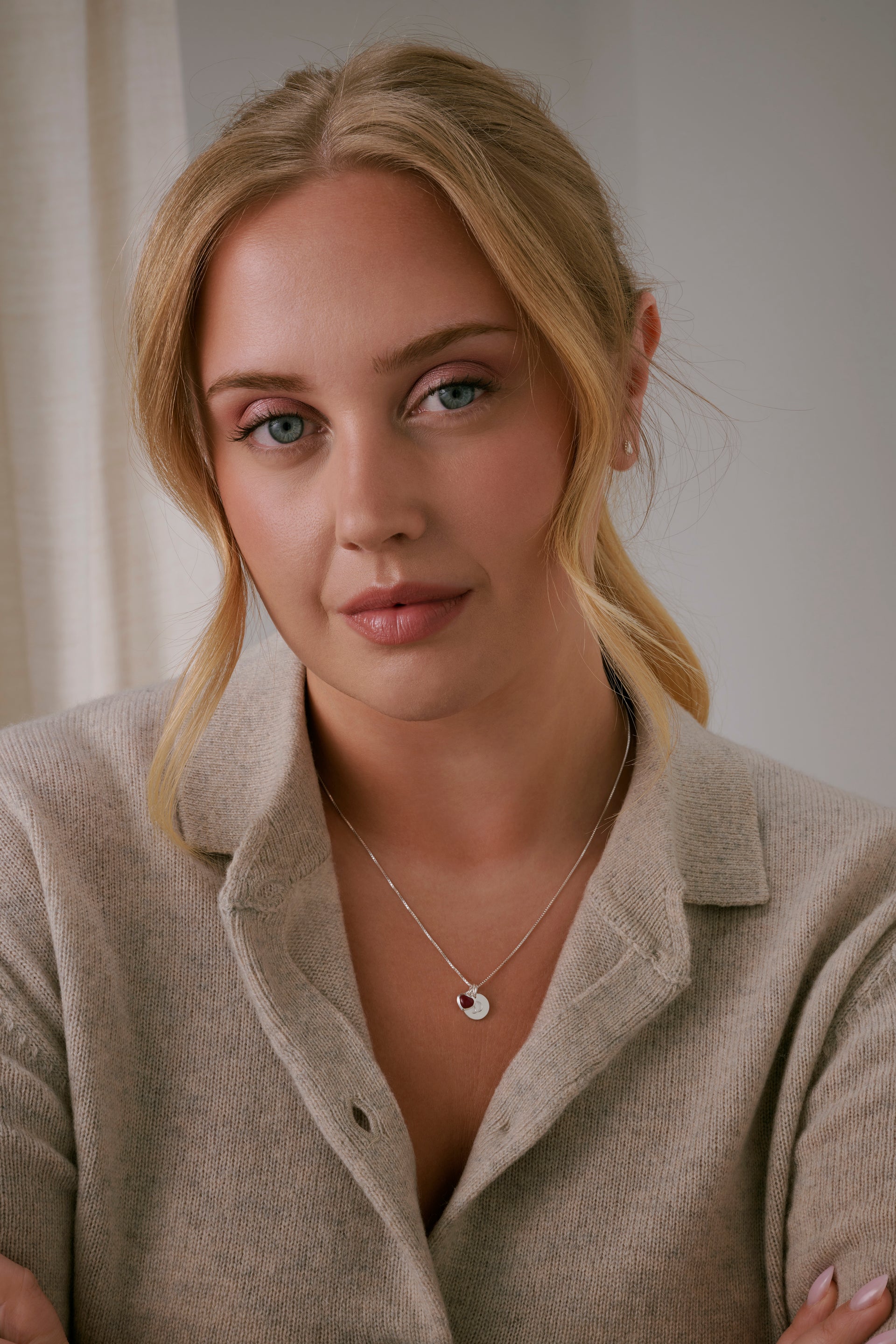 The medium-length necklace is adorned with a letter pendant and an pink heart charm