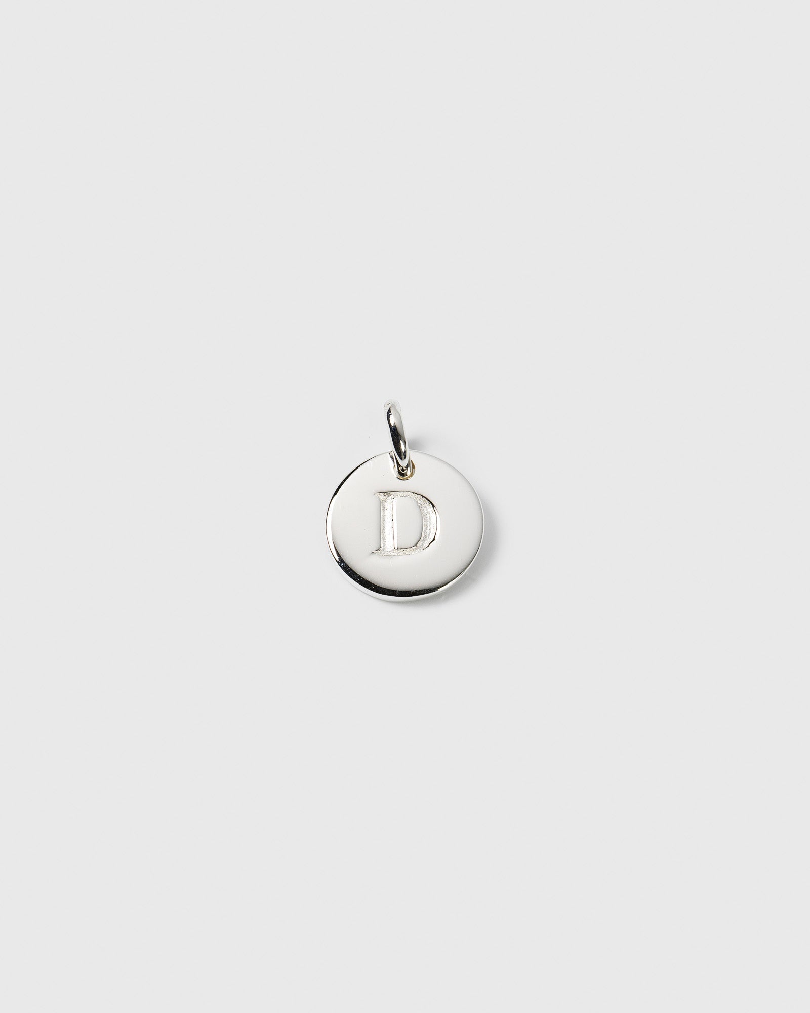 A product shot of the Beloved Mini Letter charm in silver, showcasing the round pendant with the letter D engraved on it.