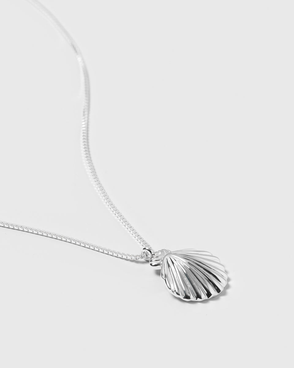 A product shot of the Beaches Shell Necklace in silver, featuring a delicate chain and a detailed shell-shaped pendant.