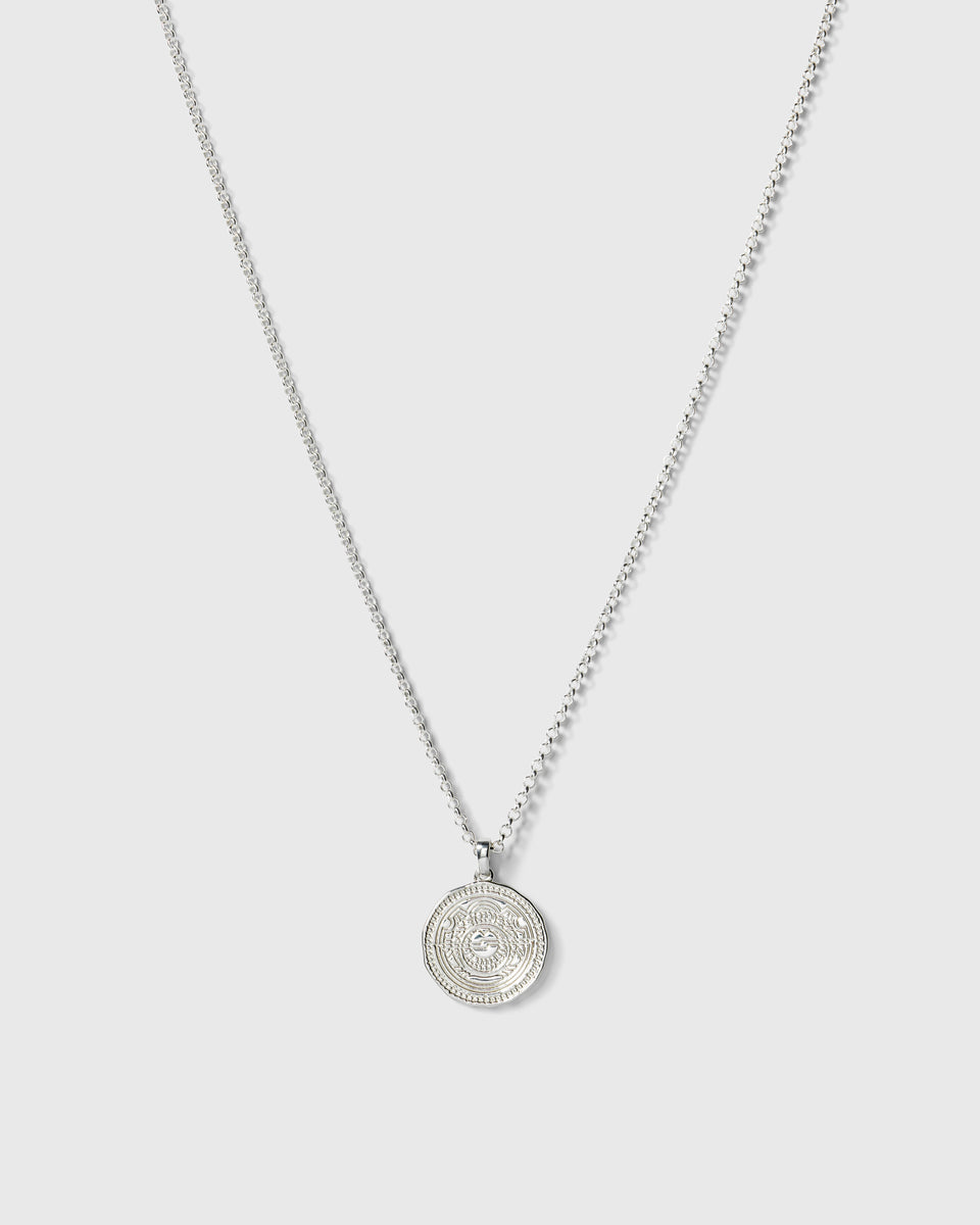 A product shot of the Lucky Coin Navigate Necklace in silver, featuring a thin ball chain and a round, coin-like pendant with a compass design.