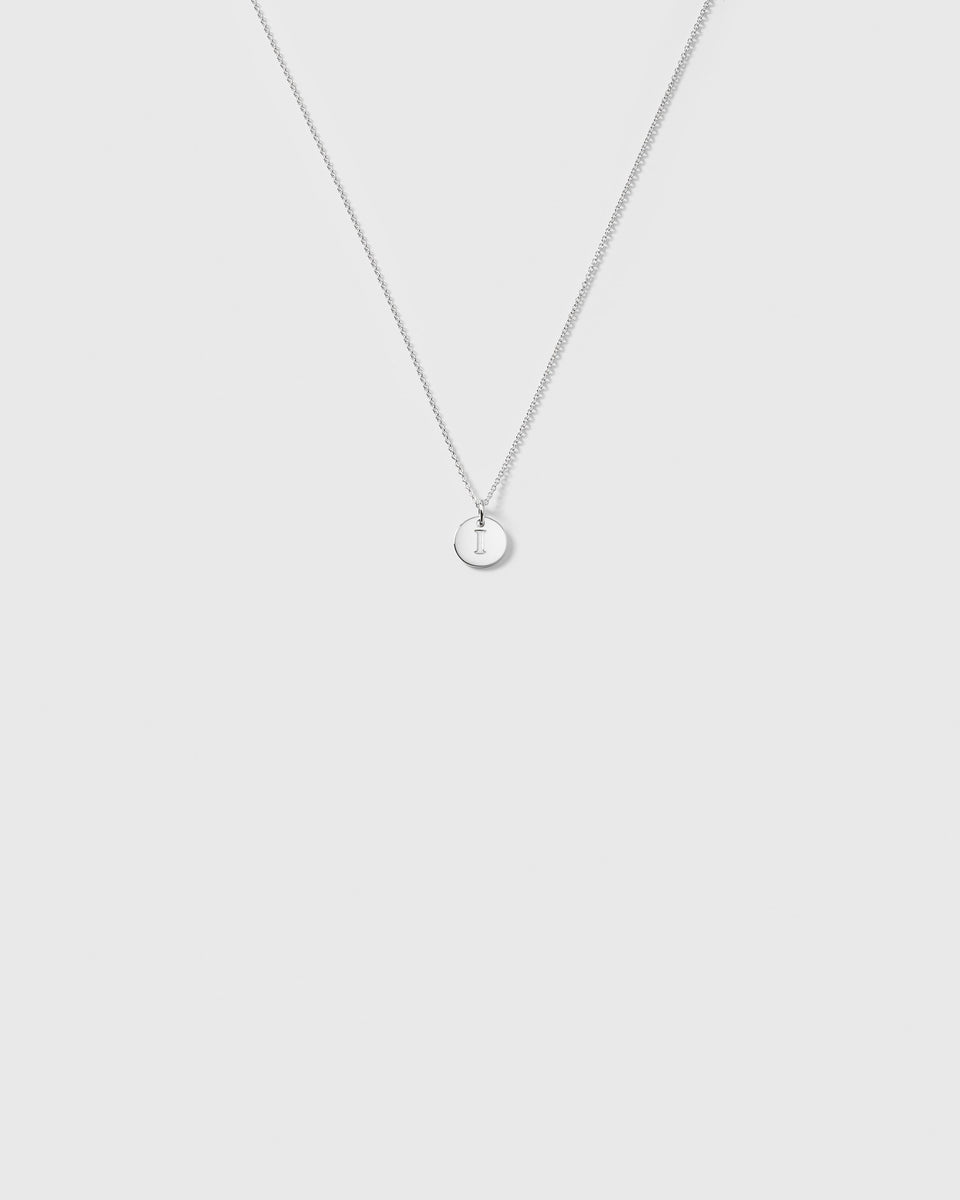 A product shot of the Beloved Baby Chain in silver, featuring the fine anchor chain styled with a small, round 'I' letter pendant.