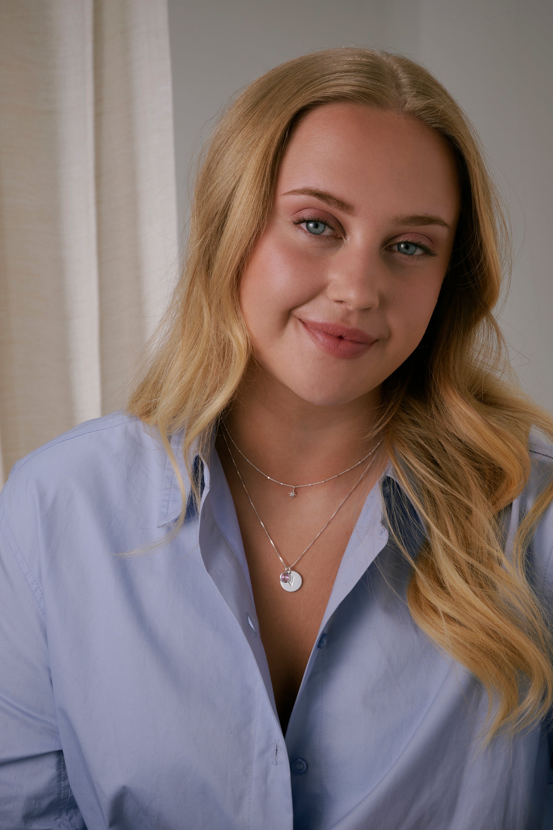 A silver necklace featuring a sparkling star pendant with a crystal and layered with a longer silver necklace.