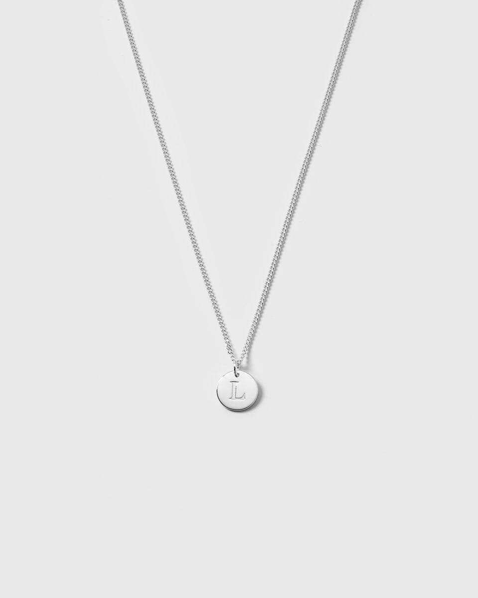 A product shot of the Beloved Short Curb Chain in silver, featuring a round pendant engraved with the letter L.
