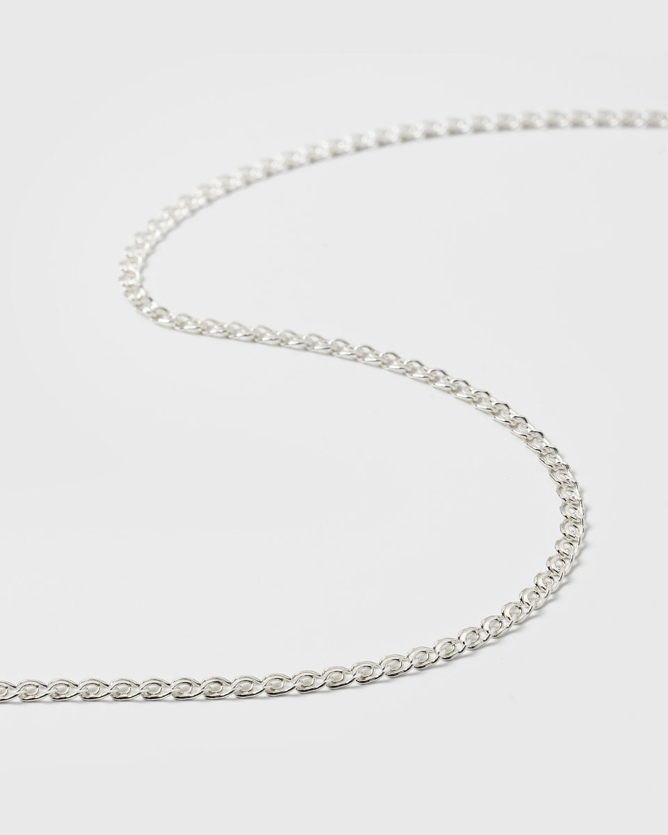 A close-up product shot of the Sheer Love Necklace in silver, laid out in a gentle curve to showcase its unique, patterned chain link design.