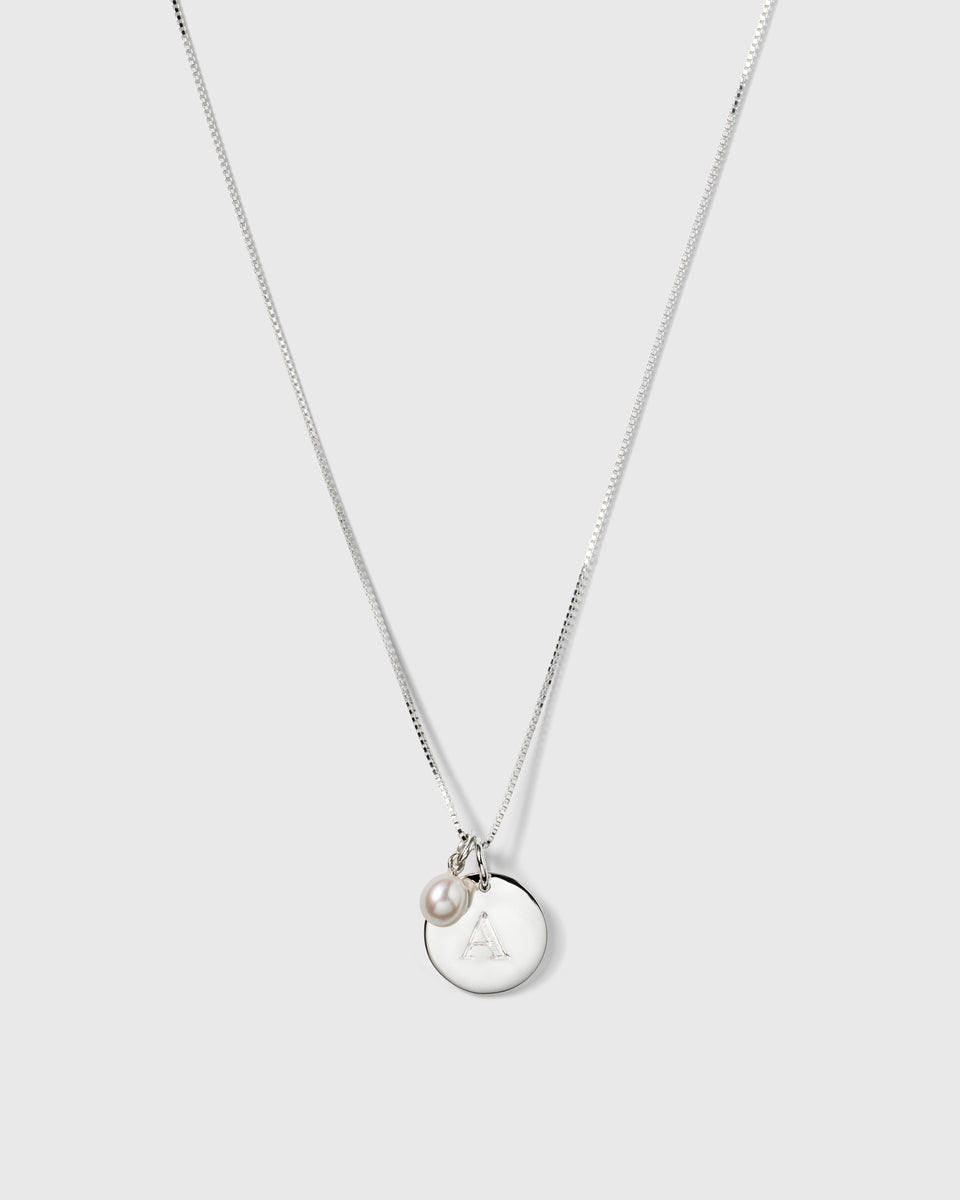A product shot of the Beloved Pearl Pendant in silver, styled on a box chain with a round silver pendant engraved with the letter 'A'.