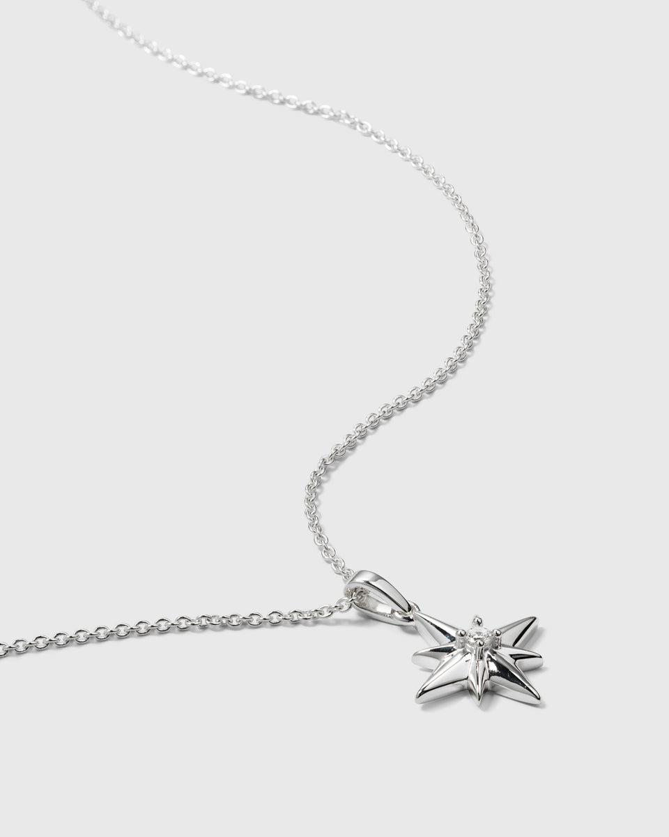 A close-up product shot of the North Star Big Necklace in silver, featuring a delicate chain and a North Star pendant with a crystal at its center.