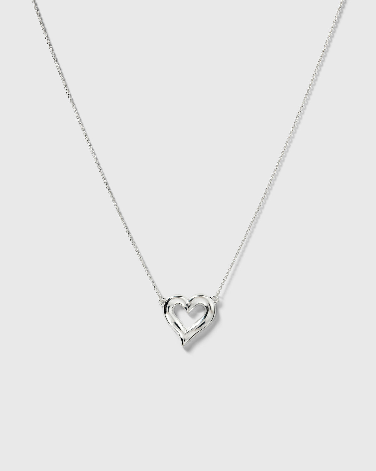 A product shot of the Puff Heart Necklace in silver, featuring its delicate chain and chunky, organic heart-shaped pendant.