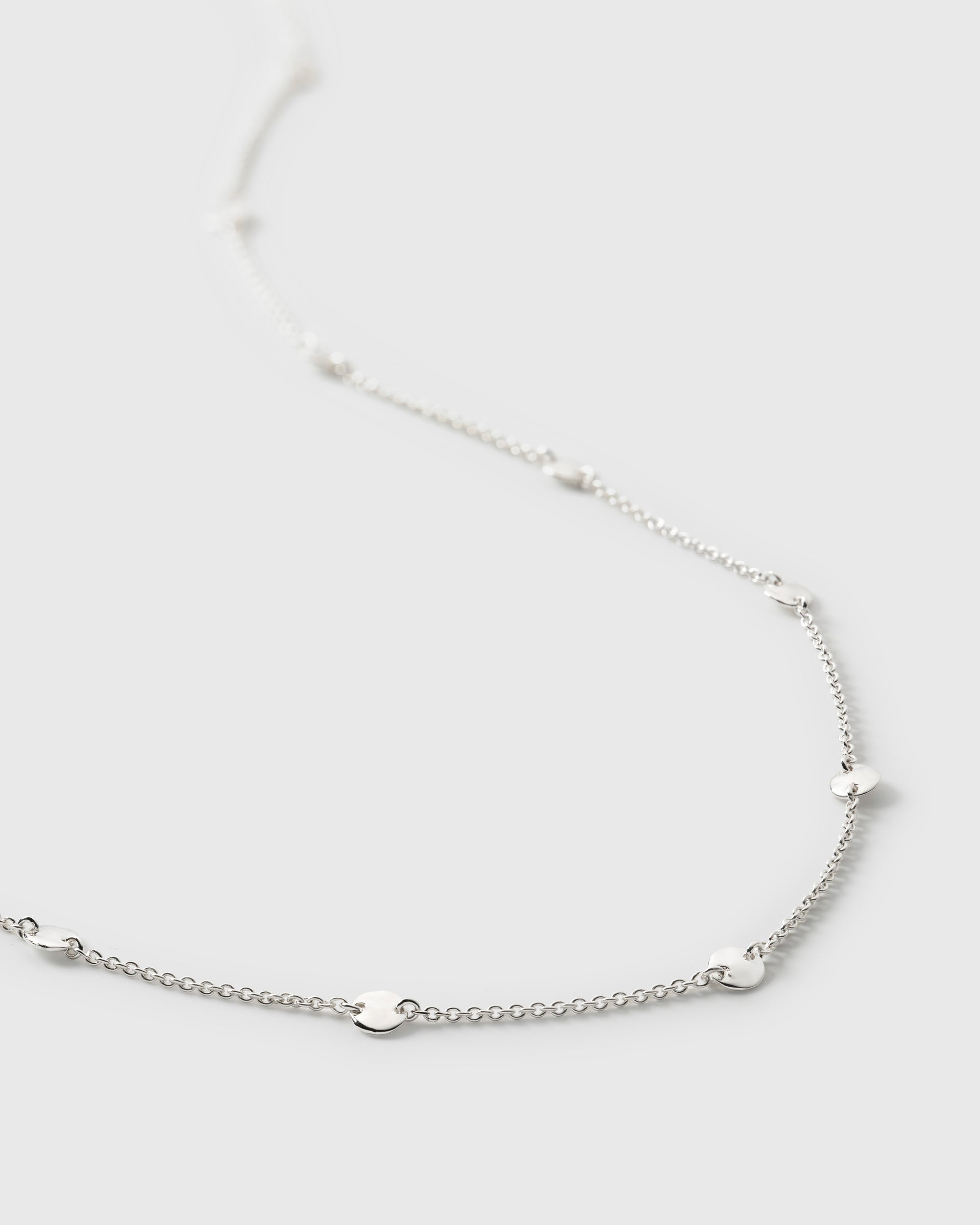 A close-up image of the Solea Necklace in silver, detailing the fine chain and the small, hammered, round circles spaced along it.