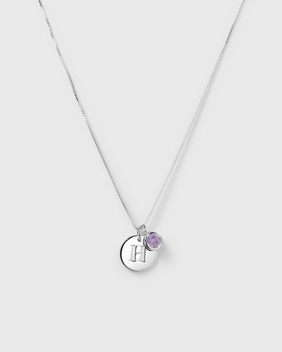Silver necklace with two pendants: a February birthstone amethyst and a round letter charm.