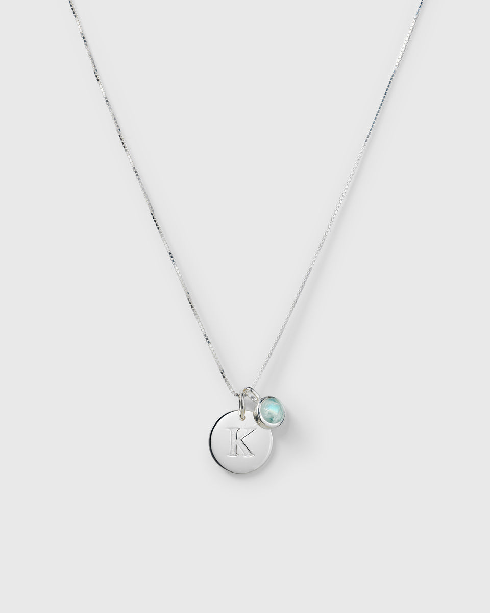 Silver necklace with two pendants: a June birthstone moonstone and a round letter charm.