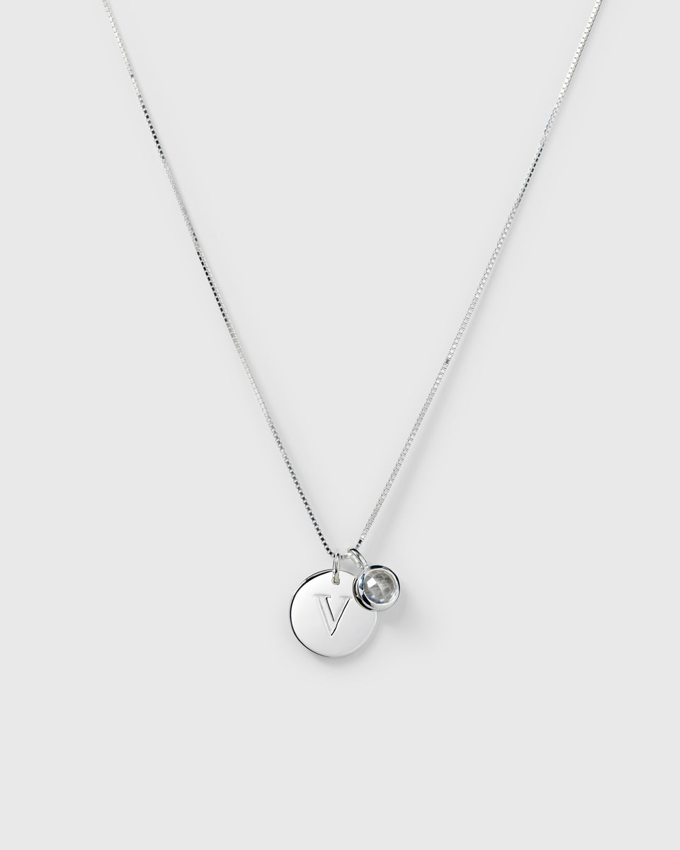 Silver necklace with two pendants: an April birthstone white topaz and a round letter charm.