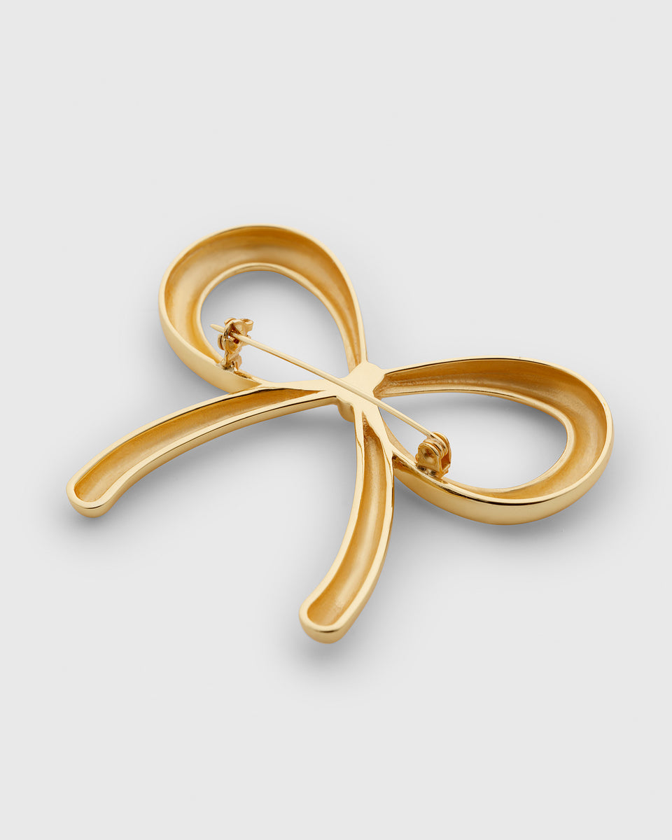 A product shot of the back of the Ana Brooch in gold, showcasing its bow design and pin closure.