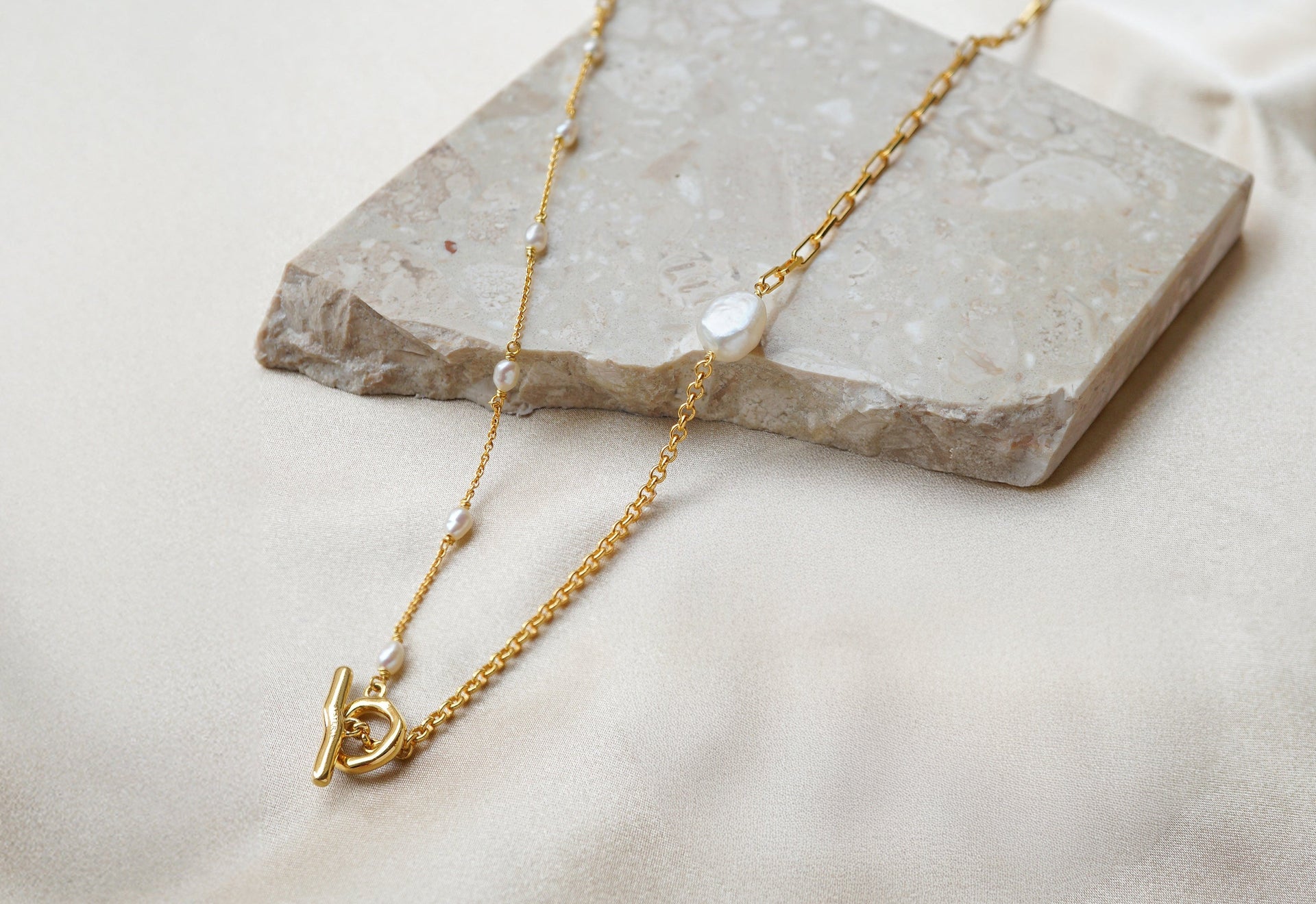 Gold necklace with a pendant on a stone surface