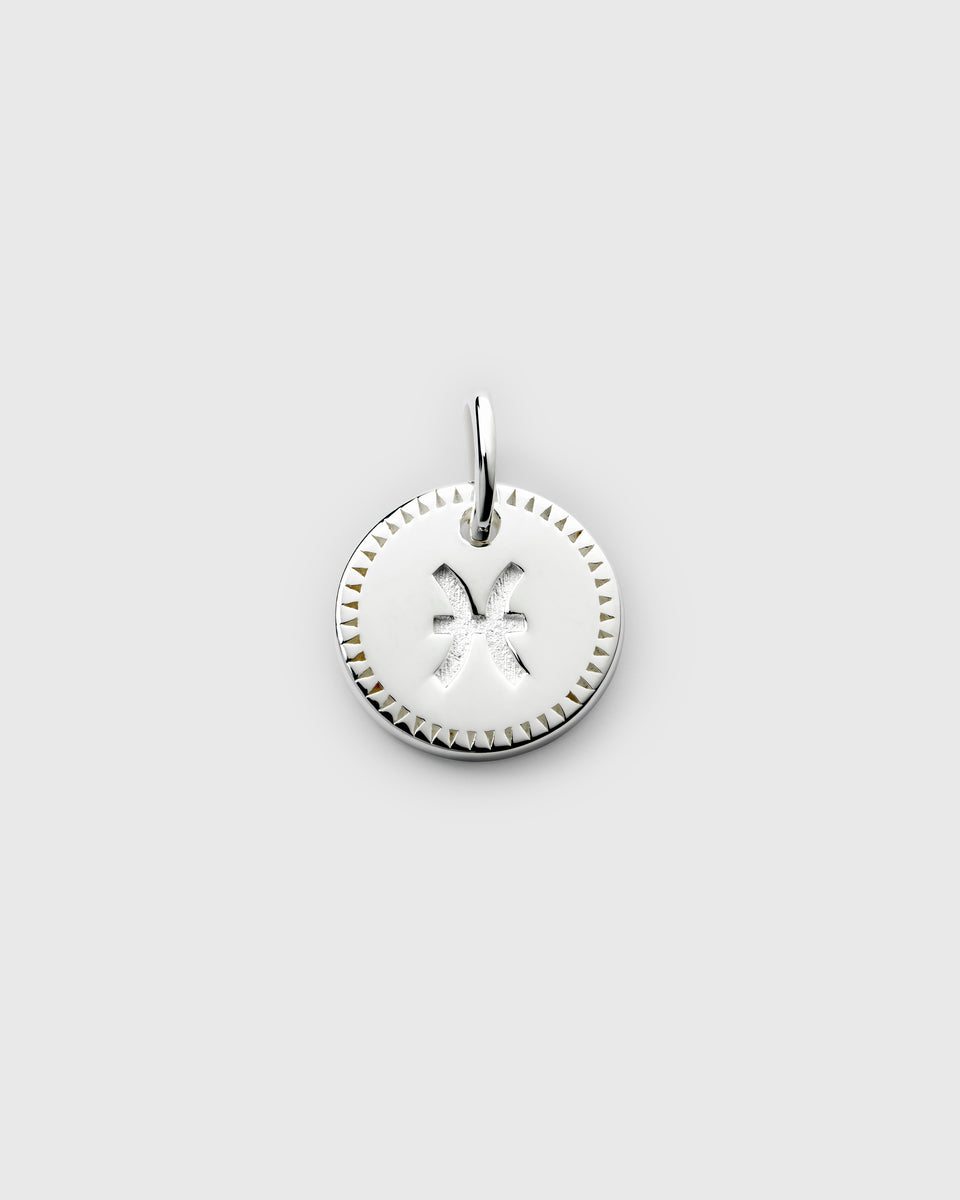A product shot of the Beloved Zodie Pendant in silver, featuring the Pisces zodiac sign engraved on the circular charm, which is framed by a decorative triangular border.