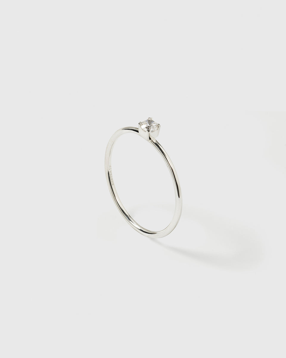 A product shot of the Tiny Princess Ring in silver, featuring a thin band and a single round, faceted crystal in a princess setting.