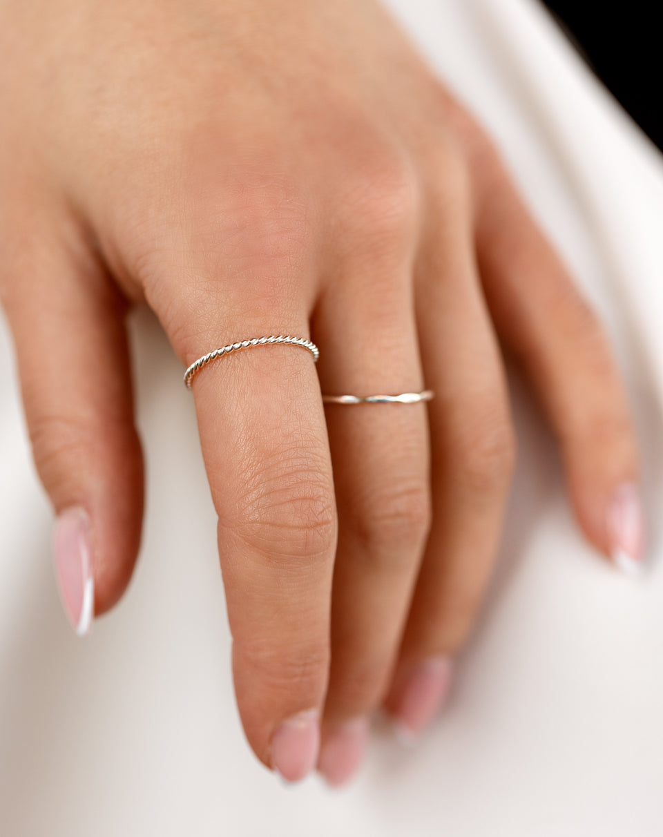 A model wears the Tiny Twisted Ring in silver on her index finger, styled with a second simple, thin silver ring on her middle finger.