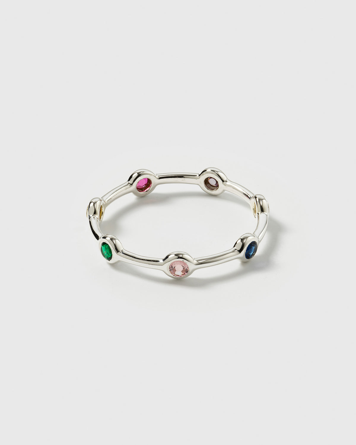 A product shot of the Treasure Shimmer Ring in silver, showcasing its delicate band design set with various colorful, faceted zirconias.