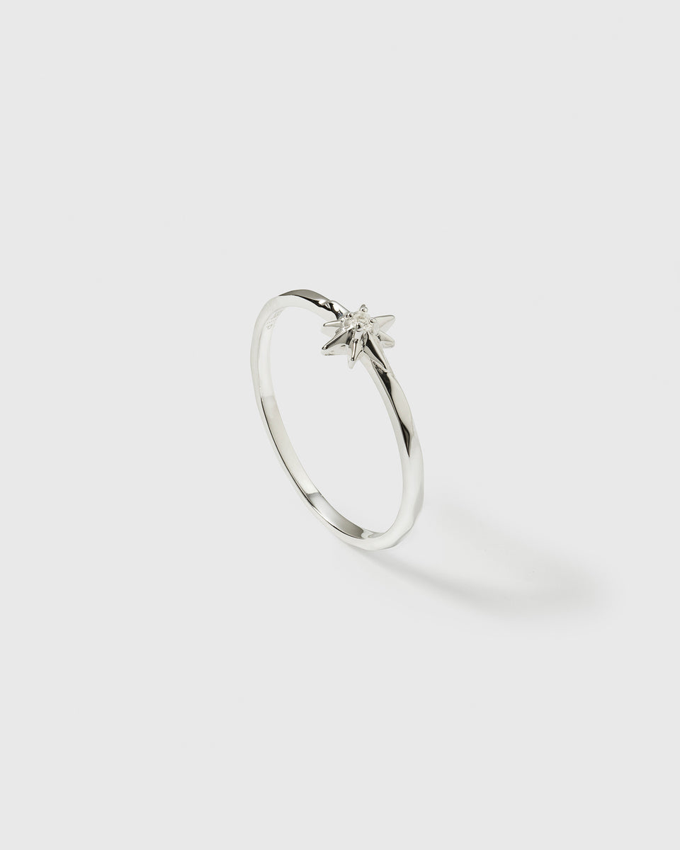 A product shot of the North Star Ring in silver, displaying its thin band and a star-shaped setting with a small crystal at its center.