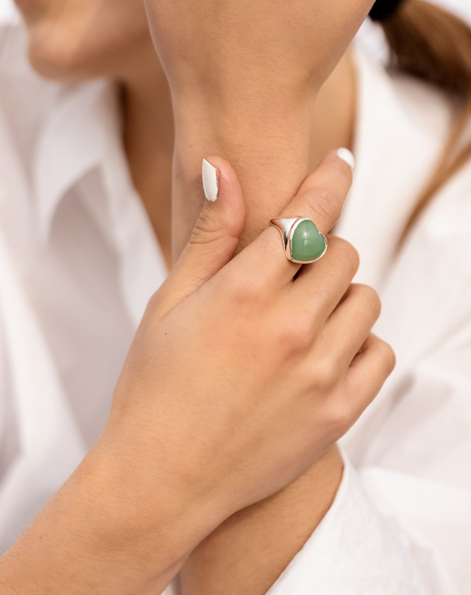 A close-up shot of a model wearing the La La Love Big Heart Ring in silver, featuring a large green jade heart.