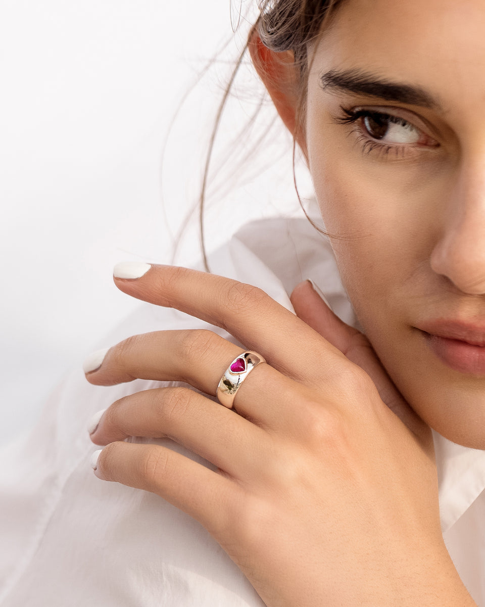 A model wears the La La Love Ring, a chunky recycled sterling silver band featuring a vibrant pink quartz heart.