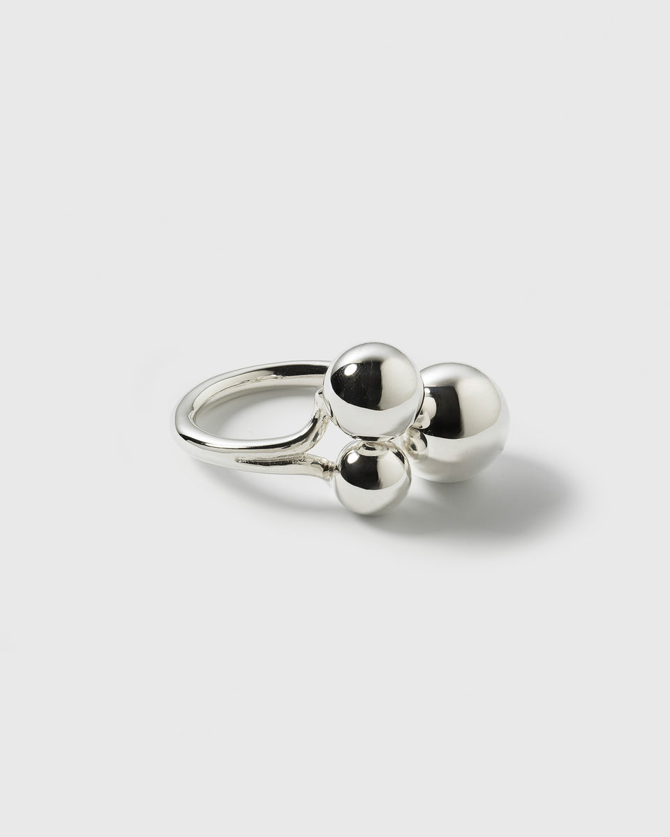 A product shot of the Universe Ring Silver, featuring a simple band with three polished spheres of different sizes clustered on top.