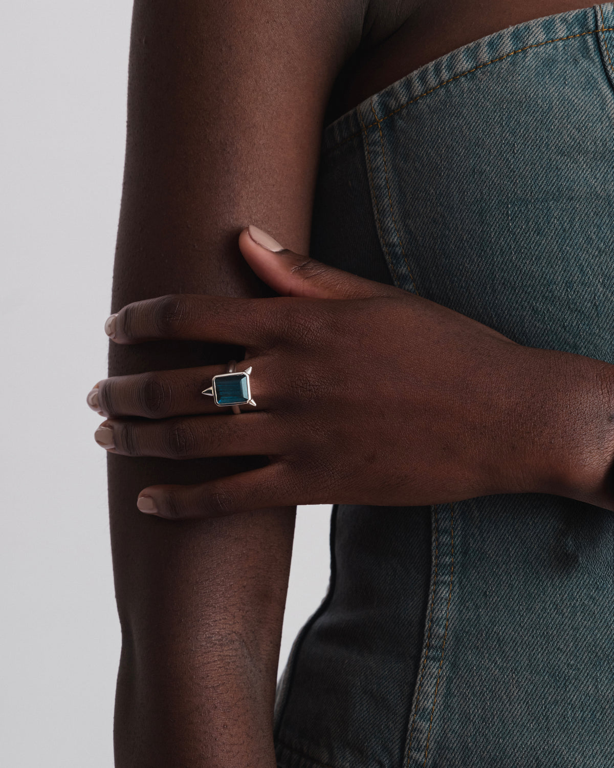 A model wearing the Drama Ring in silver, showcasing its large rectangular labradorite stone and three edgy spikes.