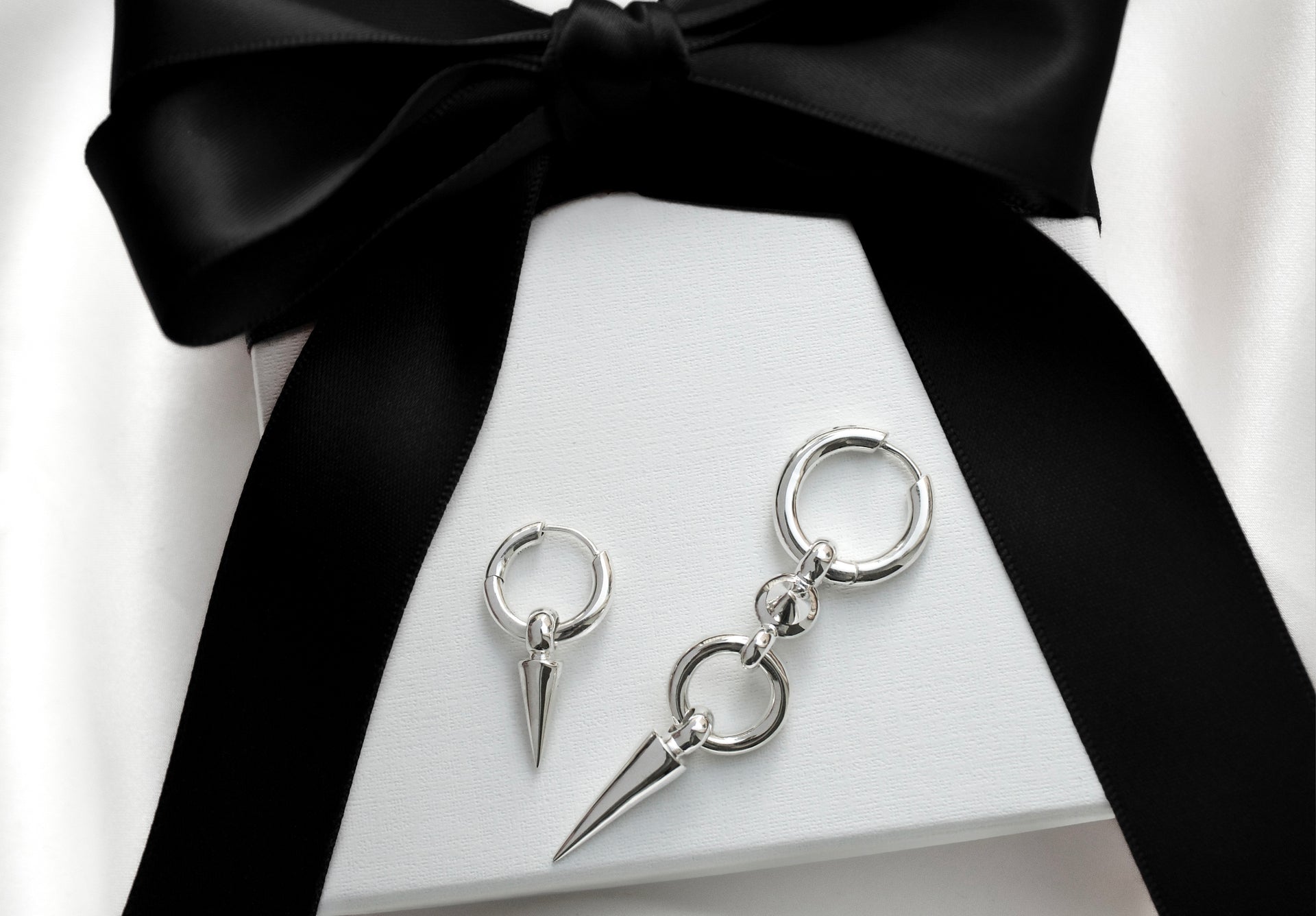 Two earrings with spikes in silver on top of a giftbox 