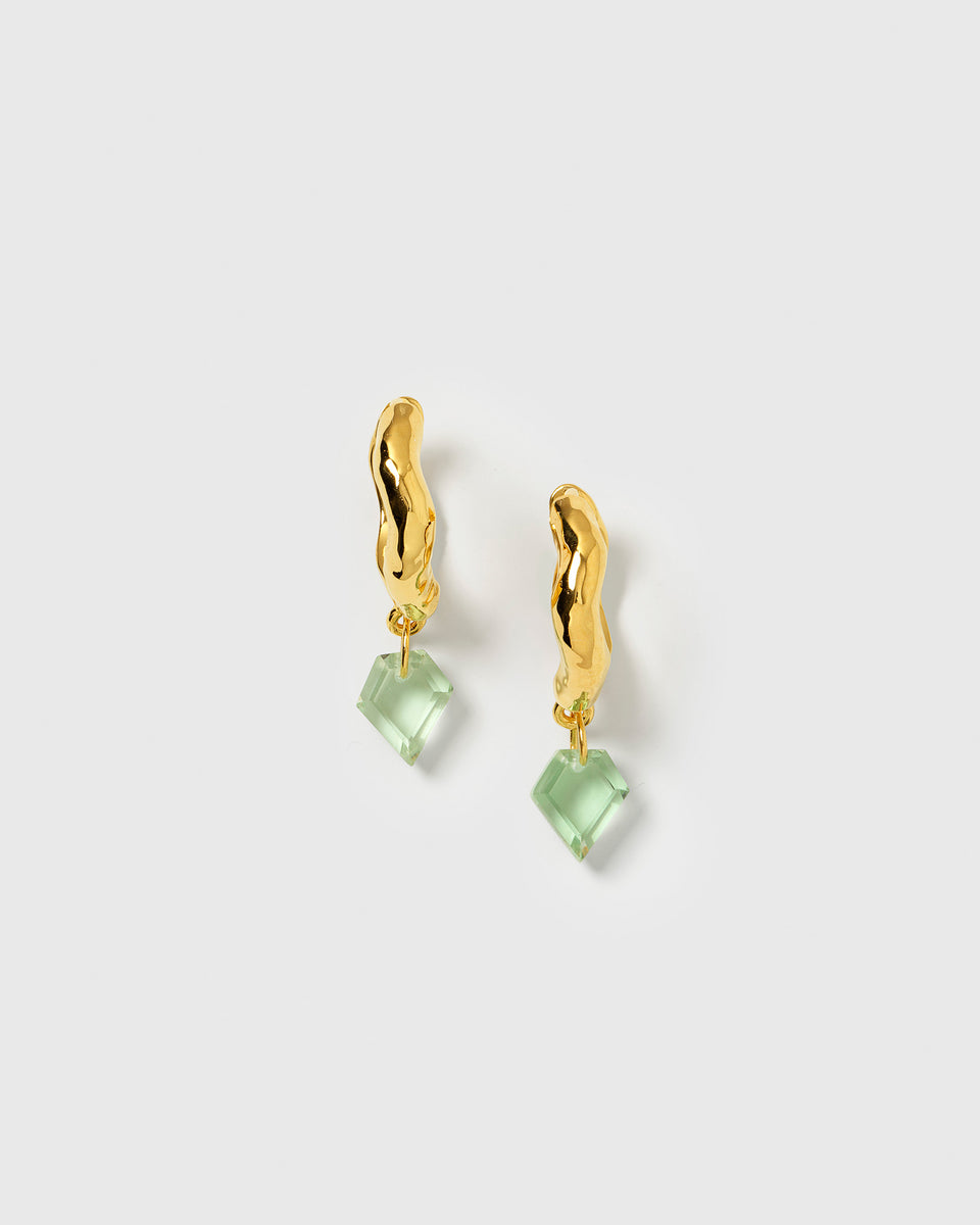 A product shot of the Diamona Earrings in gold, featuring a wavy hoop with a hammered surface and a dangling, diamond-shaped green quartz stone.