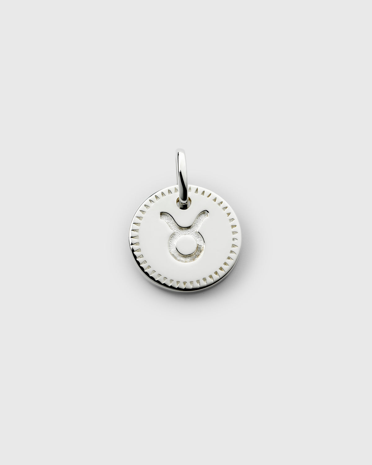 A product shot of the Beloved Zodie Pendant in silver, featuring the round Taurus charm with its engraved zodiac symbol and decorative border.
