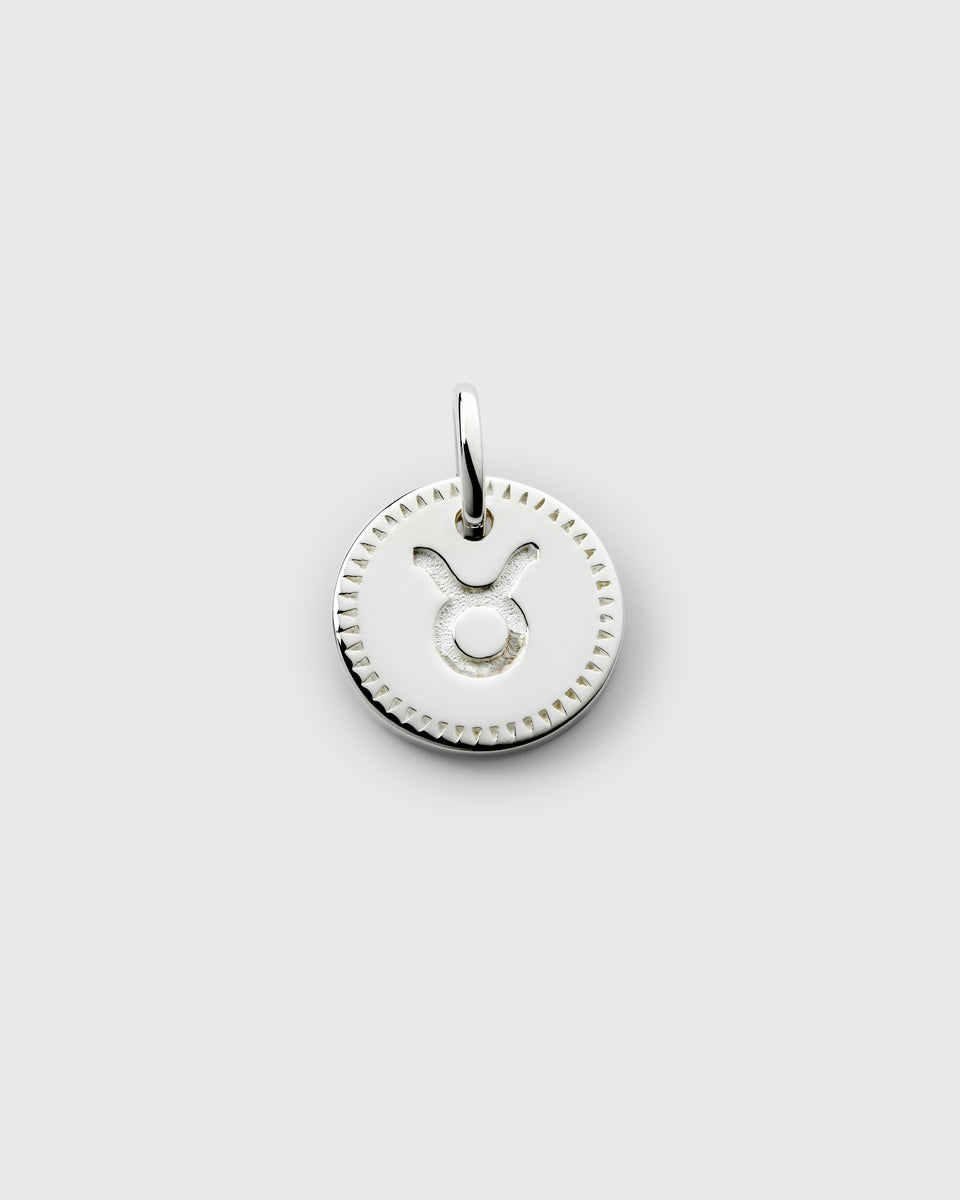 A product shot of the Beloved Zodie Pendant in silver, featuring the round Taurus charm with its engraved zodiac symbol and decorative border.