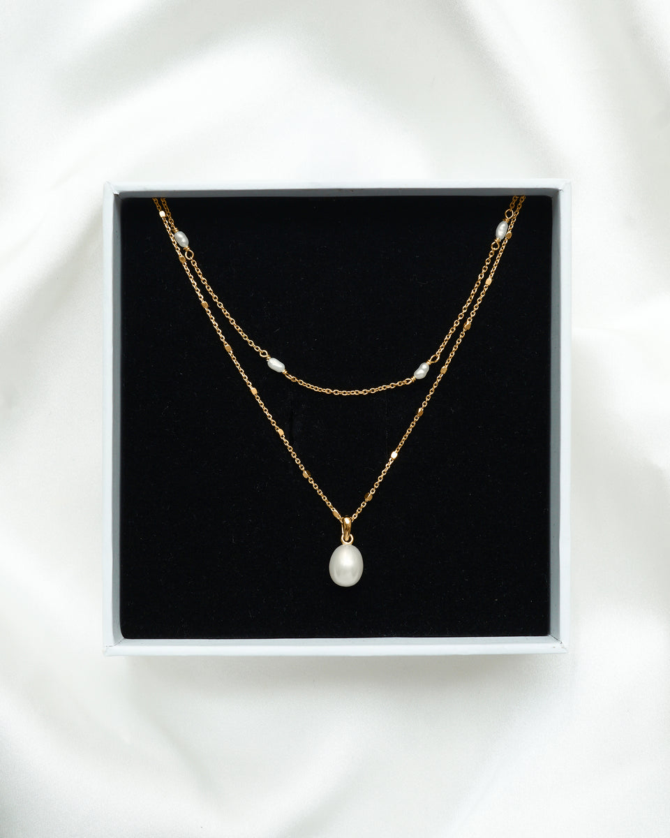 The Treasure Necklace Set in gold, featuring two layered freshwater pearl necklaces, presented inside a white Syster P gift box.