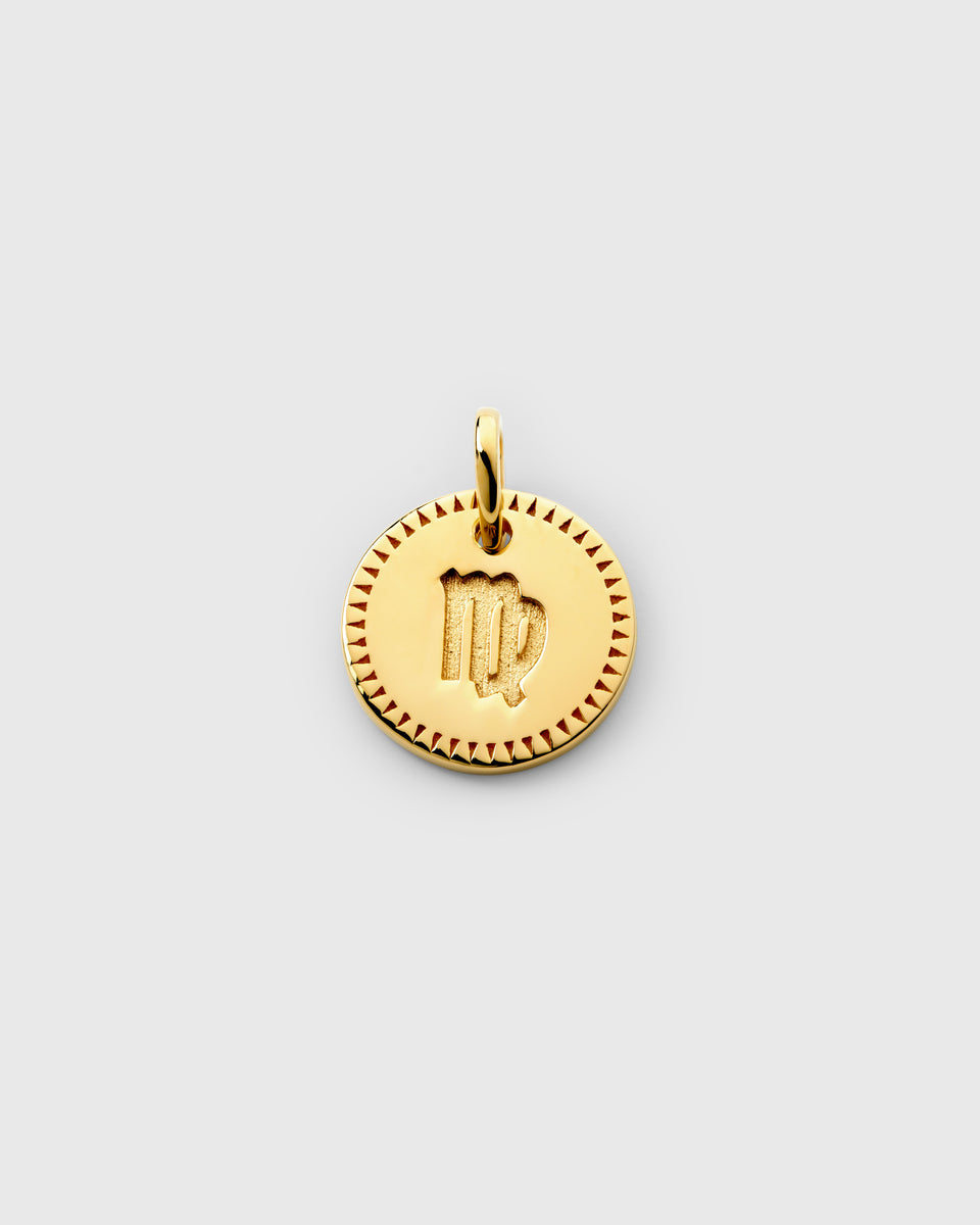 A product shot of the Beloved Zodie Pendant in gold, featuring the Virgo variant with its engraved zodiac symbol in the center, framed by a decorative border.