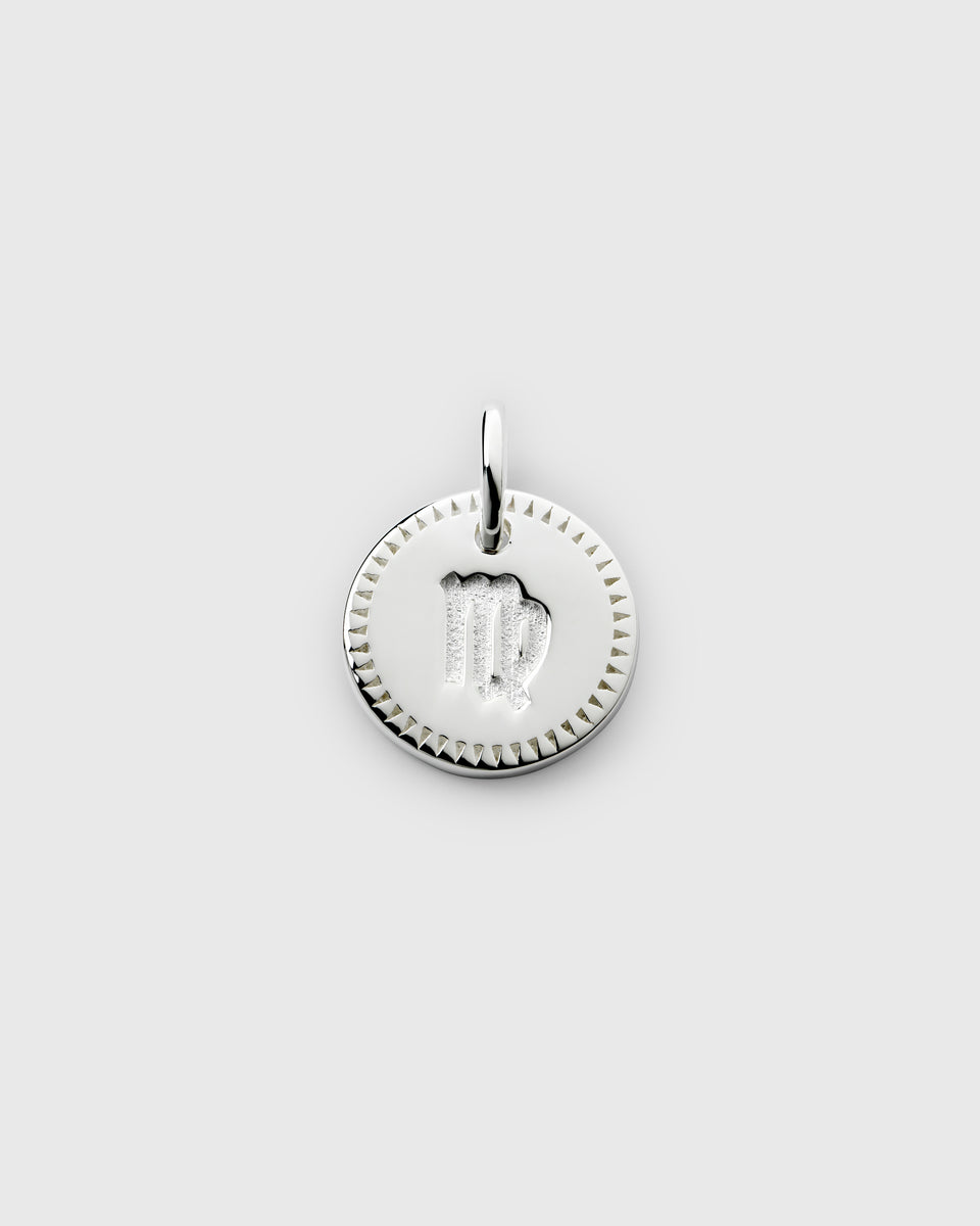 A product shot of the Beloved Zodie Pendant in silver, featuring the Virgo zodiac sign engraved in the center of the circular charm and framed by a decorative border.